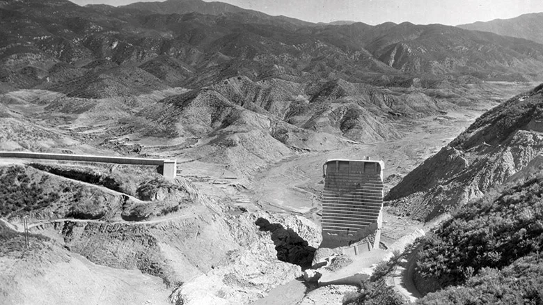 Picture of the St. Francis dam after its collapse. All that remains is a small section of the original retaining wall. The carnage of flood water is evident.